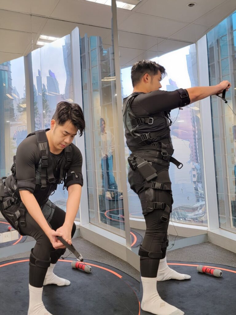 <img src="A male doing a a legs and waist exercise by using cable, wearing electric suits stimulating="示範使用阻力索，身穿電衣作刺激軀幹訓練">