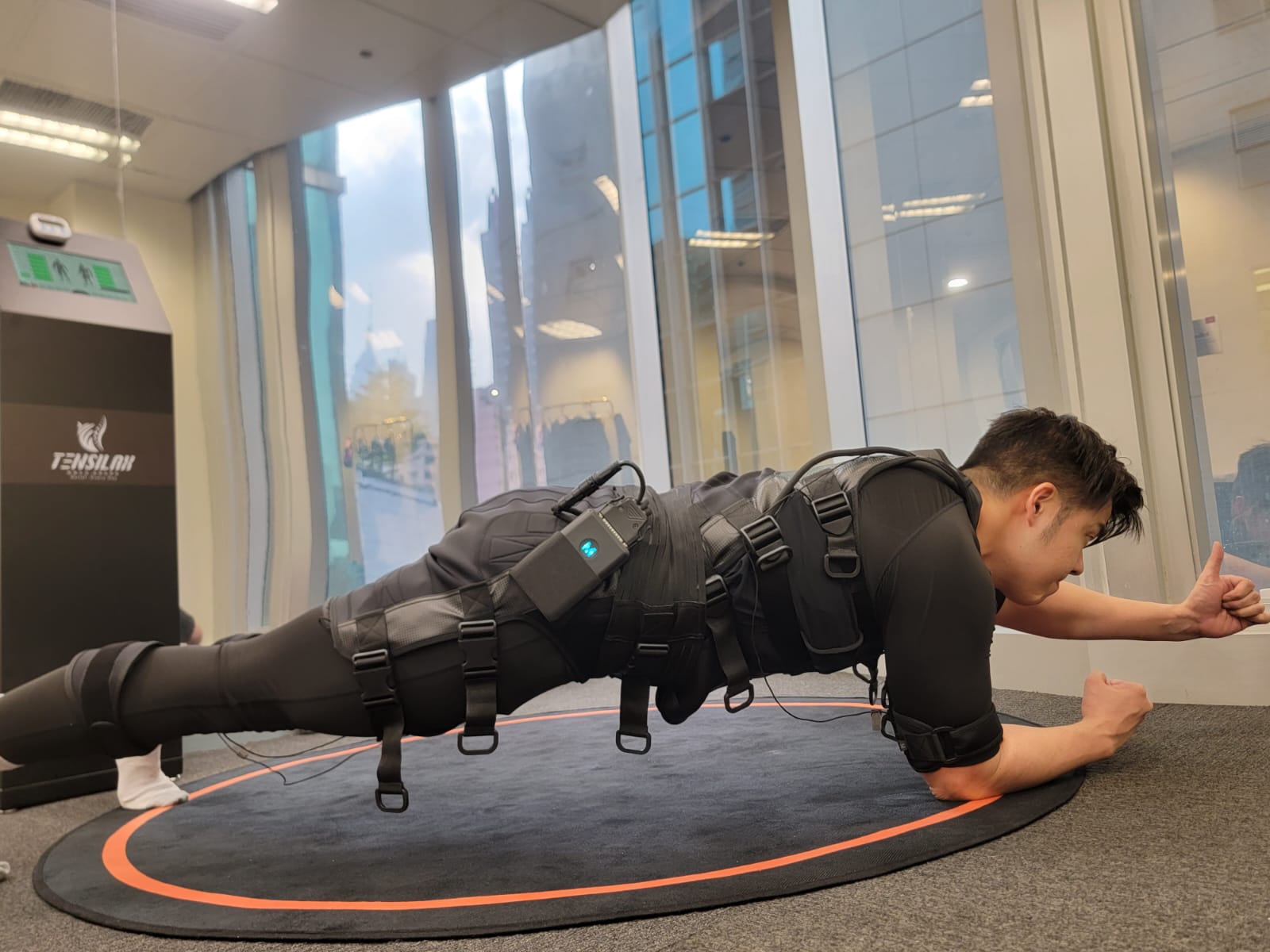 <img src="A male doing a plank pose, while single arm support the body, the other arm in the middle of air, wearing electric suits stimulating abdominal muscles="男子示範單臂平板支撐，身穿電刺激衣服作刺激腹部訓練">